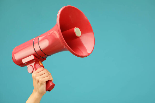 Woman holding megaphone speaker on blue background, closeup. Space for text