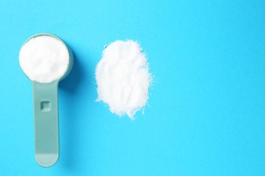 Mavi arka planda çamaşır tozu ile kepçeyi ölçmek. Metin için boşluk