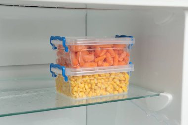 Buzdolabında farklı donmuş sebzeler olan plastik kaplar.
