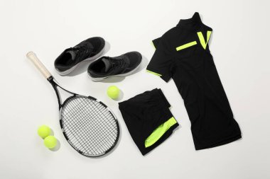 Tenis raketi, toplar ve beyaz arka planda spor giyimi, düz yatış