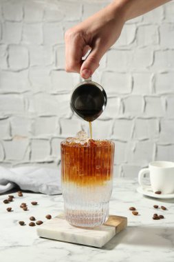 Beyaz mermer masada taze espresso tonik hazırlayan kadın, yakın plan.