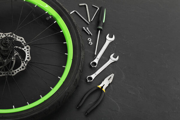 Bicycle wheel and tools on black background. Space for text