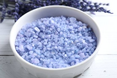 Beyaz ahşap masada doğal deniz tuzu ve lavanta çiçekleri, yakın plan.