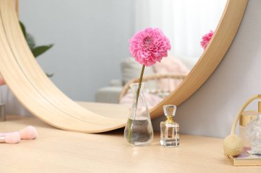 Aynalı giyinme masası, kozmetik ürünler ve kapalı alanda çiçek. İç tasarım