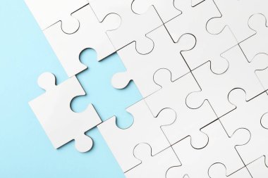 Açık mavi arkaplanda beyaz yapboz parçaları, üst görünüm