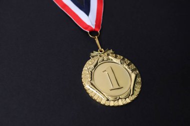 Siyah arkaplanda çizgili kurdeleli altın madalya, yakın plan