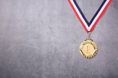 Gri arka planda çizgili kurdeleli altın madalya, üst manzara. Metin için boşluk