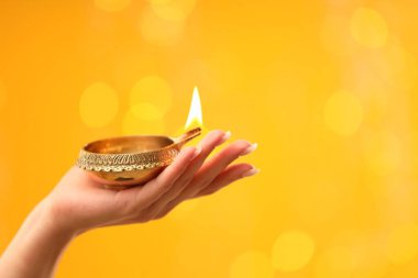 Diwali kutlaması. Sarı arka planda yanan, bulanık ışıkları olan bir kadın, yakın plan. Metin için boşluk