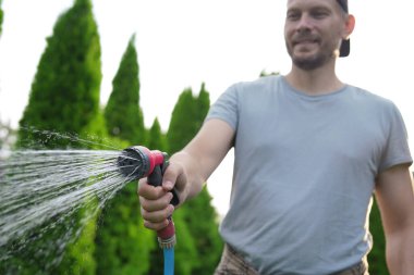 Bahçede hortumla çimenleri sulayan adam, seçici odaklanma