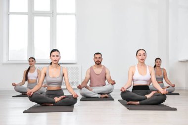 Yoga dersinde minderler üzerinde meditasyon yapan bir grup insan.