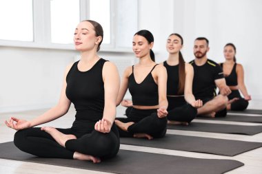 Yoga dersinde minderler üzerinde meditasyon yapan bir grup insan.