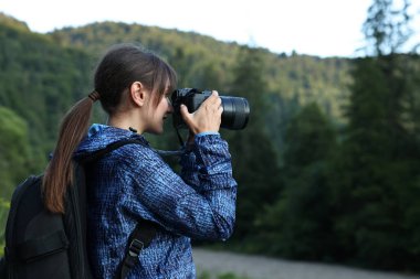 Sırt çantalı ve kameralı fotoğrafçı güzel dağların resmini çekiyor, metin için boşluk var.