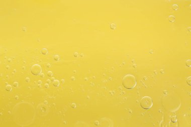 Sarı arka planda gerekli yağ kabarcıkları, makro görünüm. Kozmetik ürünü