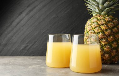 Bardakta lezzetli ananas suyu ve gri desenli masada meyve. Metin için boşluk