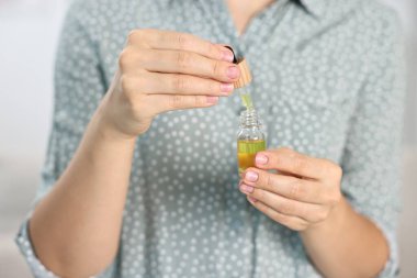 CBD tentürü alan genç bir kadın, kapalı alanda, yakın çekim