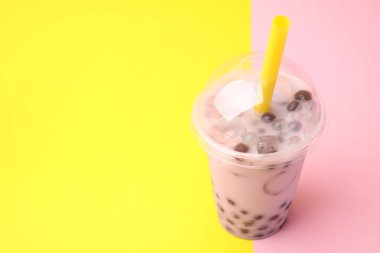 Renkli arka planda plastik fincanda lezzetli sütlü çay, metin için boşluk