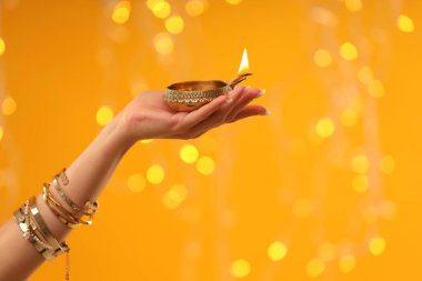 Diwali kutlaması. Elinde turuncu arka planda yanan, bulanık ışıkları olan bir kadın, yakın plan. Metin için boşluk
