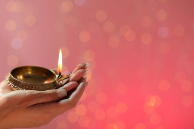 Diwali kutlaması. Elinde yanan diya lambası tutan bir kadın. Arka planda bulanık ışıklar var. Yakın plan. Metin için boşluk