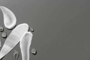 Gri arka planda farklı kozmetik ürünlerinin kokusu, üst görünüm. Metin için boşluk