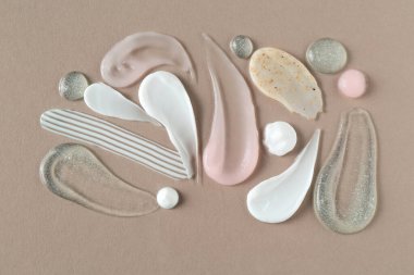 Gri arka planda farklı kozmetik ürünlerinin izleri, düz yatış