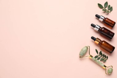 Farklı kozmetik ürünleri ve bej arka planda yeşil yapraklar. Metin için boşluk