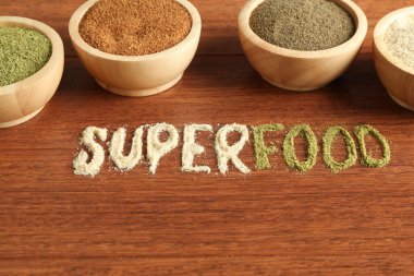 Superfood kelimesi ve ahşap masada farklı sağlıklı tozlar, yakın plan.