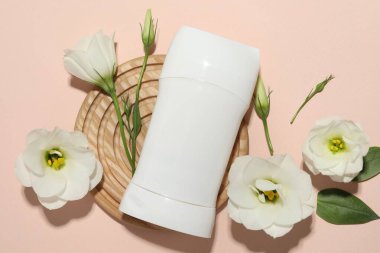 Katı deodorant ve güzel Eustoma çiçekleri bej arka planda, düz yatıyordu.