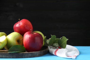 Açık mavi ahşap masada taze kırmızı ve yeşil elmalar