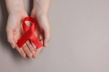 Gri arka planda kırmızı kurdeleli bir kadın, yazı için üst görüş ve boşluk. HIV (AIDS) Hastalık Bilinci