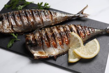 Lezzetli ızgara uskumru ve limon beyaz masada, yakın plan.