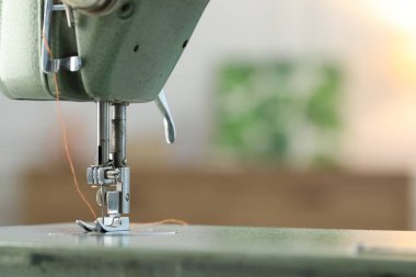 Bulanık arkaplanda ipliği olan dikiş makinesi, makro görünüm. Metin için boşluk