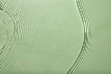 Açık yeşil zemin üzerinde dalgalı temiz su yüzeyi, üst görünüm