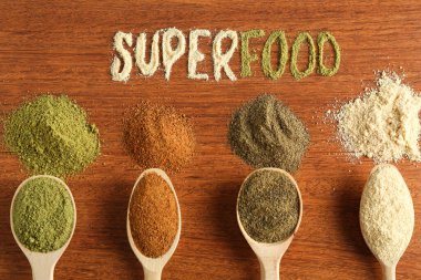 Superfood kelimesi ve ahşap masa üzerindeki farklı sağlıklı tozlar.