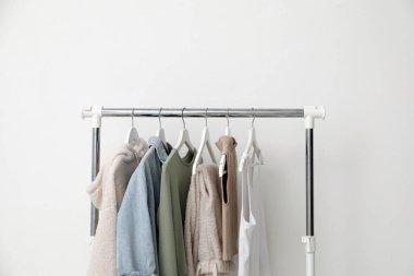 Beyaz duvarın yanında farklı kıyafetlerle dizilin.