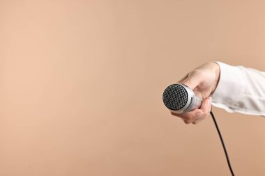 Bej arka planda mikrofonu olan bir kadın, yakın plan. Metin için boşluk