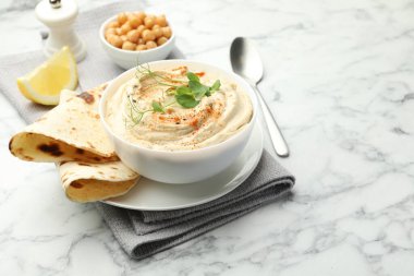 Kırmızı biberli lezzetli humus, beyaz mermer masada pide ve nohut.