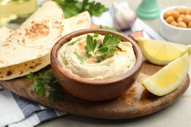 Maydanozlu lezzetli humus, paprika, pide ve limon gri masada, yakın plan.