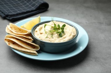 Lezzetli humus kasede, pide ve limon gri masada, yakın plan.