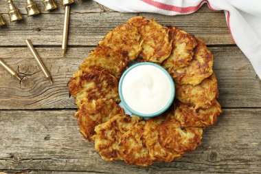 Lezzetli patates krepleri, ekşi krema, menorah ve ahşap masa üzerindeki mumlar, düz yatak. Hanuka bayramı yemekleri.