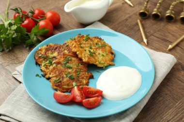 Lezzetli patates krepleri, menorah ve ahşap masada mumlar, yakın plan. Hanuka bayramı yemekleri.