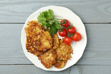 Lezzetli patates krepleri, domatesler ve maydanoz gri ahşap masa, üst manzara
