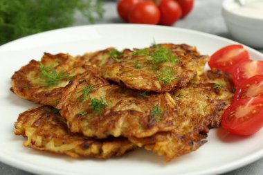 Delicious potato pancakes with fresh tomatoes and dill on table, closeup clipart