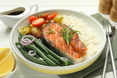 Lezzetli ızgara somon bifteği pilav ve sebzeler beyaz ahşap masada, yakın plan.