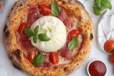 Beyaz masada servis edilen burrata peyniriyle nefis bir pizza.