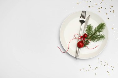 Beyaz arka planda tabak, çatal bıçak takımı ve şenlik dekoruyla Noel sofrası. Metin için boşluk