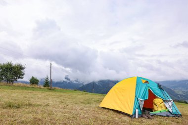 Dağlardaki çimlerin üzerinde kamp çadırı ve turistik şeyler, metin için yer.