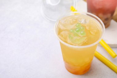 Tasty bubble tea in plastic cups and straws on light table, closeup. Space for text clipart