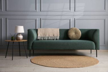 Rahat bir kanepe ve gri duvarın yanındaki yan masa.