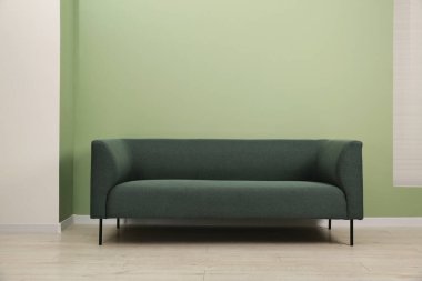 Yeşil duvarın yanında şık bir kanepe.