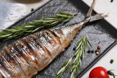 Lezzetli ızgara uskumru, biberiye ve biberiyeler gri masada, yakın plan.